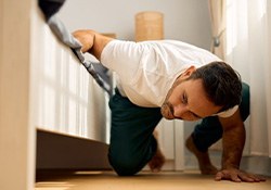 Man looking under bed for lost item
