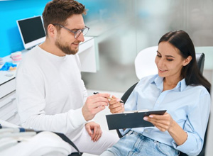 Dental patient preparing to sign document on clipboard