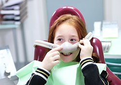 Smiling girl pointing at her nitrous oxide nasal mask