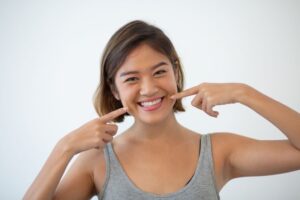 Happy young woman pointing at her teeth